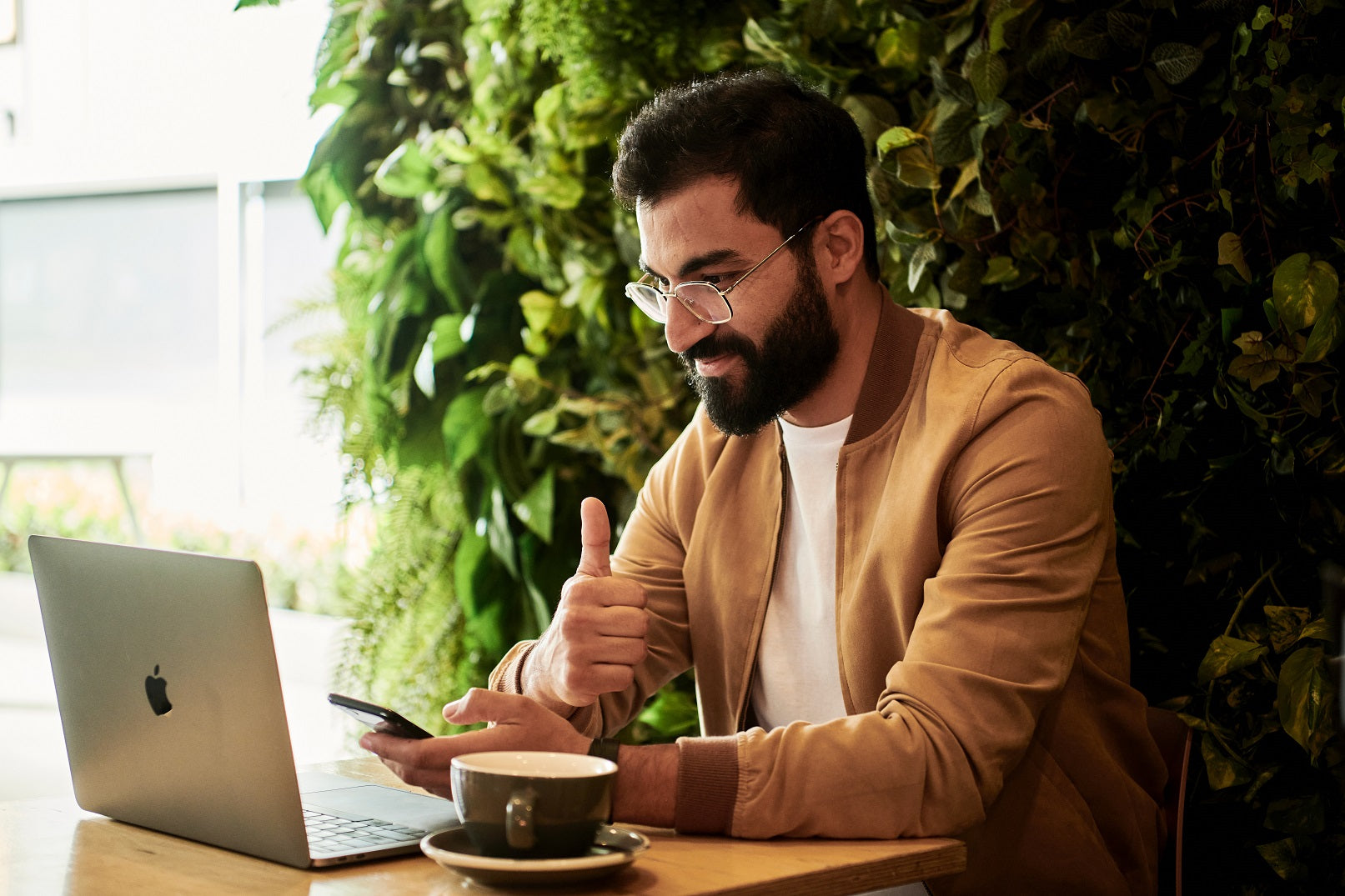 Braunhaariger Mann mit Laptop und Kaffee